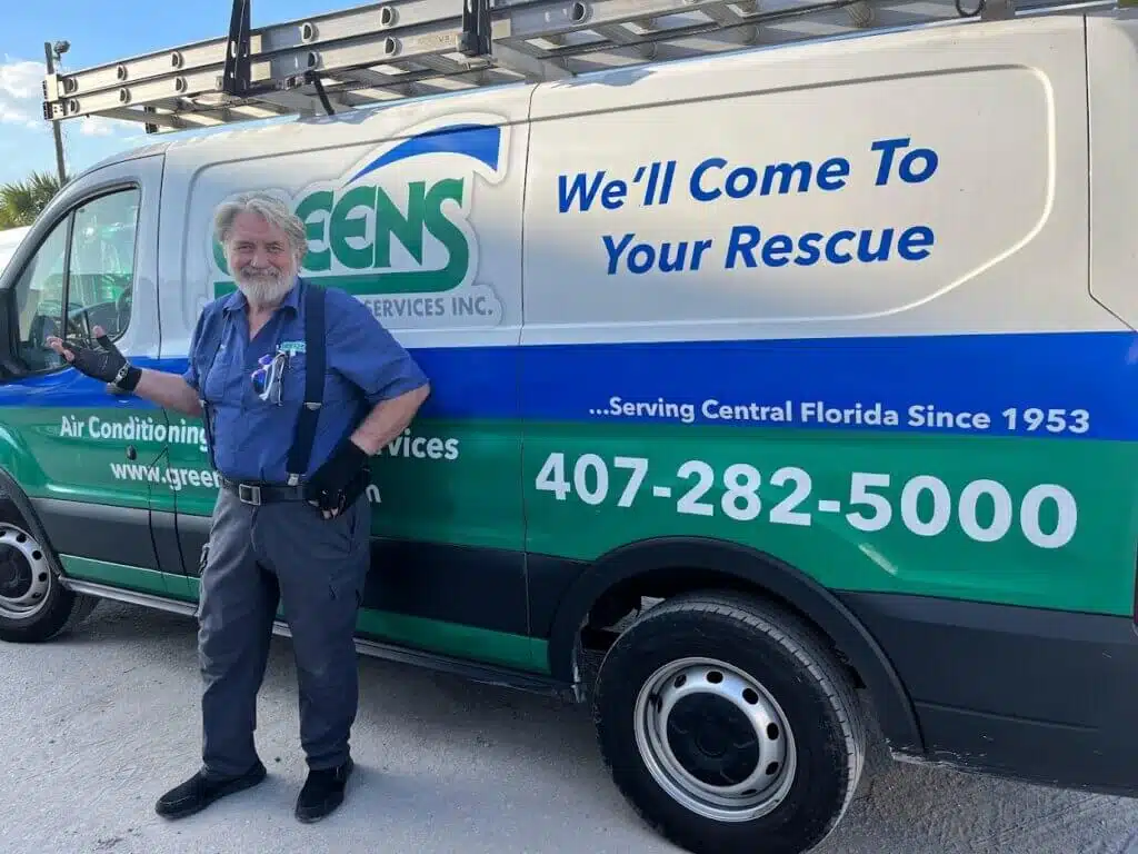 Tony from Greens Energy posing in front of a work van that says "We'll Come To Rescue You" and includes phone number.